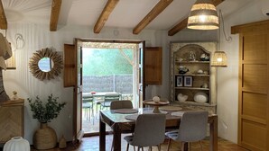 A rustic dining area with a wooden table, chairs, and a hanging light fixture. - Charming sheepfold with private heated pool between sea and mountains (Sotta)