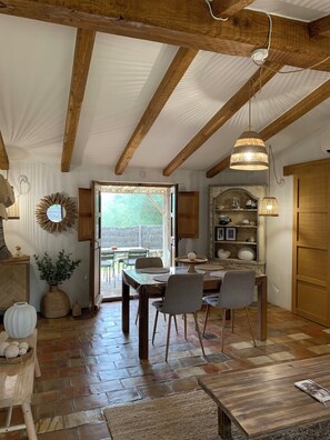 A rustic dining area with a wooden table, chairs, and a hanging light fixture.
