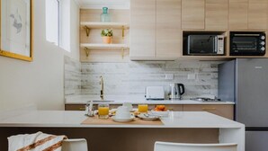 Una cuina moderna amb una illa central, microones integrat, torradora i nevera.