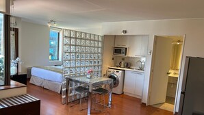 Un apartament modern amb zona de menjador, cuina i una finestra gran amb vistes.