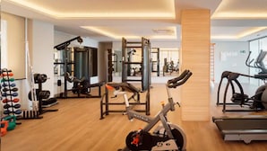Un gimnasio moderno con máquinas de cardio, pesas libres y un espejo grande.