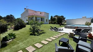 A house with a swimming pool, outdoor furniture, and a well-maintained lawn. - Charming House Galé (Grândola)