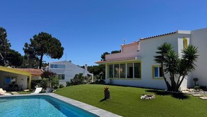 A modern house with a swimming pool, a well-maintained lawn, and a clear blue sky. - Charming House Galé (Grândola)