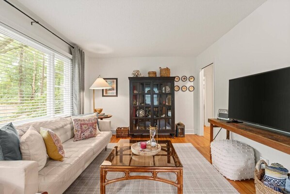 A living room with a sofa, coffee table, and a television.
