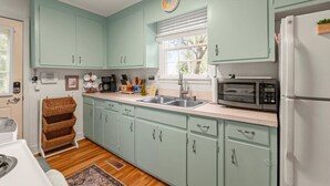 A kitchen with light green cabinets, a sink, a microwave, and a refrigerator.