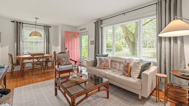 A cozy living room with a wooden coffee table, a beige sofa, and a dining area with a wooden table and chairs.