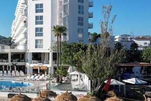 A hotel with a swimming pool, lounge chairs, and a palm tree. - Innside by Meliá Ibiza (Ibiza)