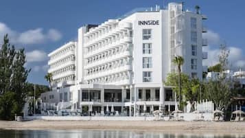 A multi-story hotel with balconies, a pool area, and a beachside location.