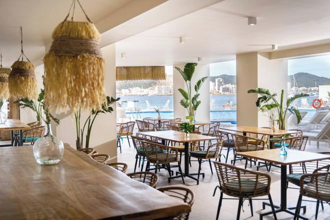 A restaurant with outdoor seating, wicker furniture, and a view of the sea.