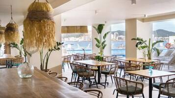 A restaurant with outdoor seating, wicker furniture, and a view of the sea.