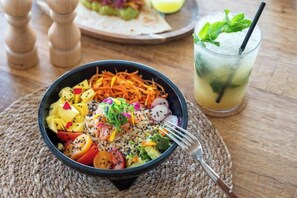 Insalata colorata in una ciotola, con una bevanda accanto, su un tavolo di legno.