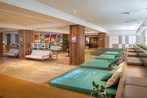 Un vestíbulo de hotel con zonas de estar, obras de arte en las paredes y un mostrador de recepción.