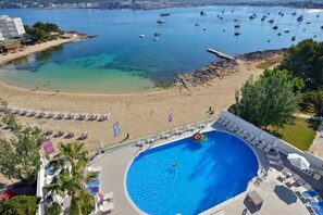 A pool surrounded by a beach area with lounge chairs and a view of the sea. - Innside by Meliá Ibiza (Ibiza)