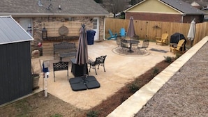 Un jardin avec un espace patio, un barbecue, du mobilier d’extérieur et un abri de jardin.