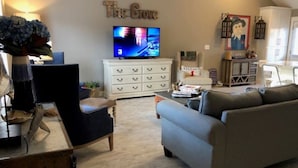 Un salon avec un téléviseur, un meuble blanc, un canapé et un fauteuil.