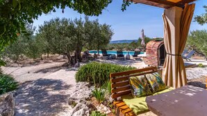 A covered outdoor area with a pool, lounge chairs, and a brick oven. - Holiday home House of the Sun - Three Bedroom Holiday Home with Pool (Sutivan)