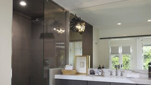A modern bathroom with a glass shower enclosure, a large mirror, and a vanity with a sink and countertop. - Fall in LOVE with The Infinity Stay Collection and enjoy the Magic it offers. (Carriere)
