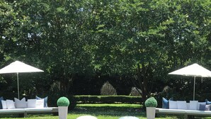 A pool with a clear view of the surrounding garden, including neatly trimmed hedges and a seating area with cushions. - Fall in LOVE with The Infinity Stay Collection and enjoy the Magic it offers. (Carriere)