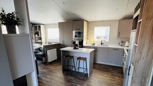 A compact kitchen with a central island, wooden flooring, and built-in appliances. - Modern, spacious lodge at Hunter's Quay Holiday Park. (Dunoon)