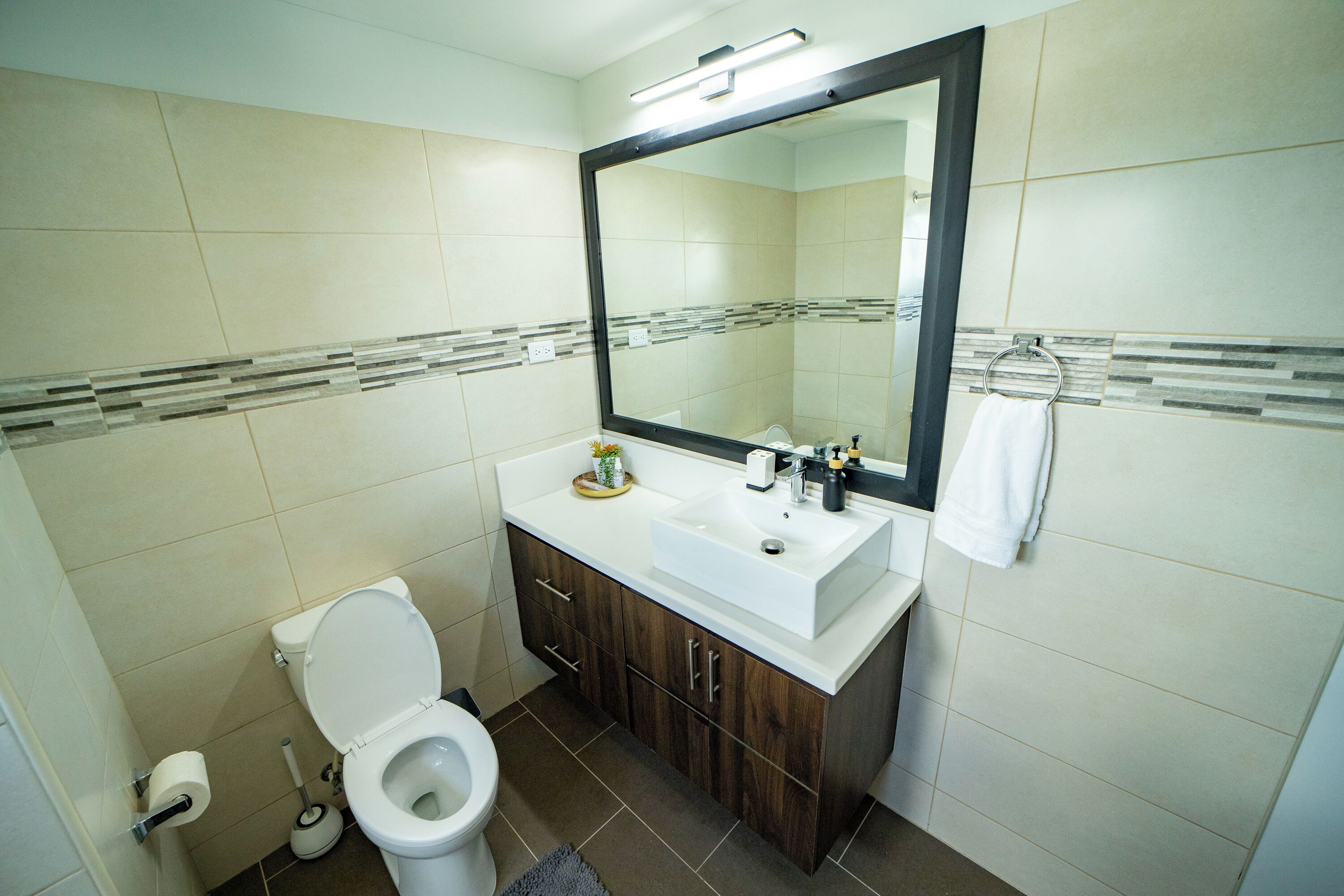 A bathroom with a toilet, sink, mirror, and towel rack.
