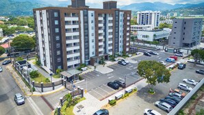 Un edificio residencial de varios pisos con un estacionamiento al frente.