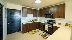 Una cocina moderna con armarios de madera oscura, un microondas de acero inoxidable y un horno empotrado.