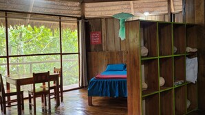 A room with a bed, a table, chairs, and a shelf with items. - Amaca Eco Station (San Juan Bautista)