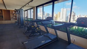 A gym with exercise equipment, large windows, and a city view.