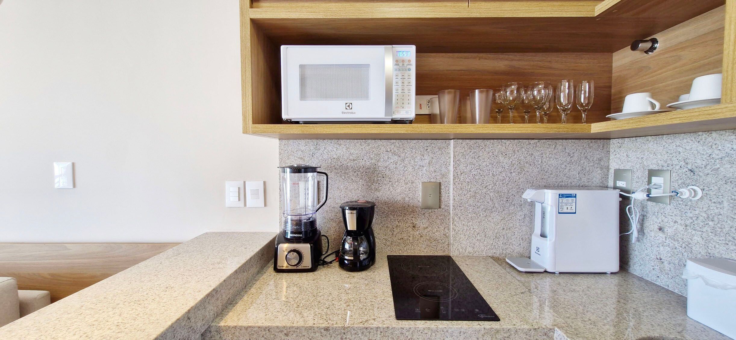 Une cuisine moderne équipée d’un four à micro-ondes encastré, d’une machine à café, d’un mixeur et d’un grille-pain.