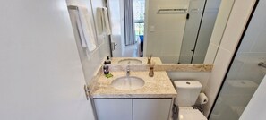 A bathroom with a sink, toilet, and a large mirror. - COBAR0132 - Edifício Blue Barra (Salvador)