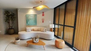 A modern living room with a curved sofa, a coffee table, and a large window with curtains.