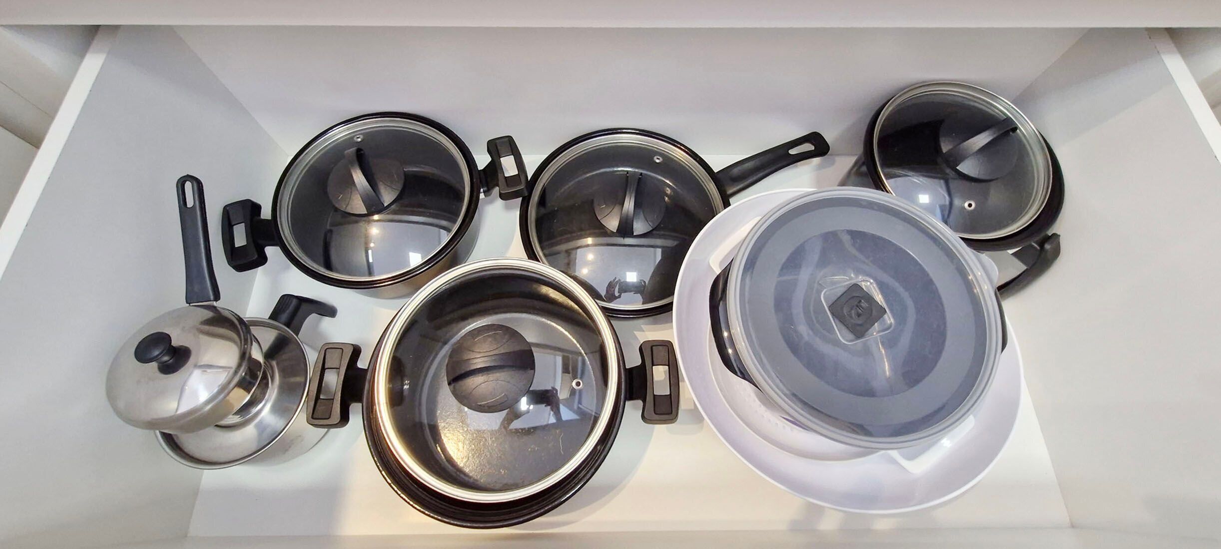 Una cucina con pentole e padelle disposte ordinatamente in un cassetto.