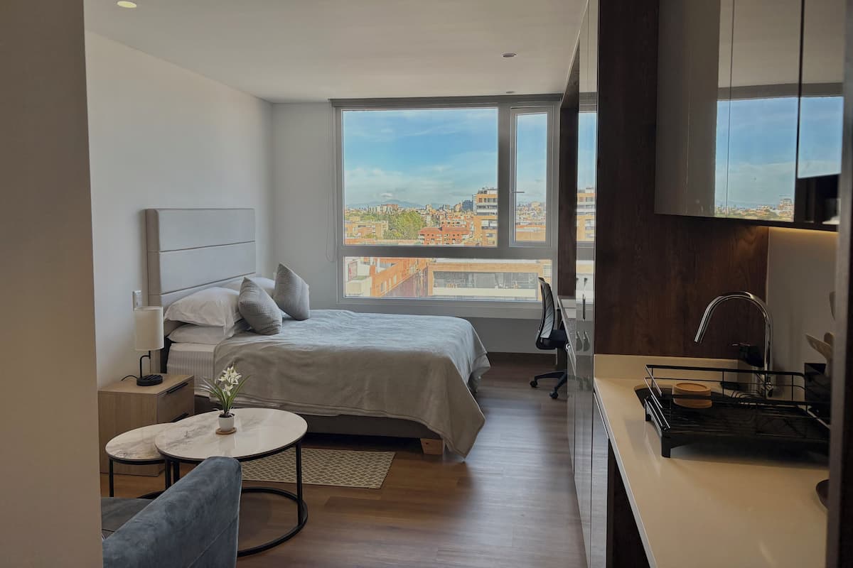 Una habitación de hotel moderna con una cama, un escritorio, una silla y vistas a la ciudad.