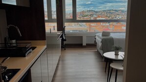 A modern kitchen with a view of a cityscape through large windows. - VOU by Wellcome (Bogotá)