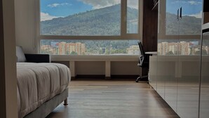 A modern bedroom with a large window, a bed, and a wardrobe. - VOU by Wellcome (Bogotá)