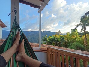 A hammock on a balcony overlooking a mountainous landscape with lush greenery. - Glamping Jardín (Jardín)