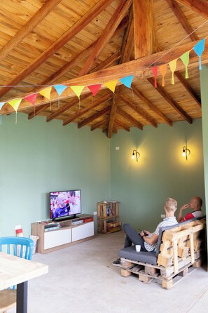 A rustic room with a wooden ceiling, a television, and a seating area with a table and chairs. - Glamping Jardín (Jardín)