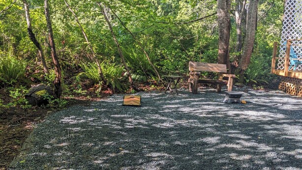 A gravel parking area with a wooden bench and a picnic table surrounded by trees. - 2-bedroom RV in beautiful Bowser with WiFi, AC (Bowser)