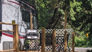 A wooden deck with picnic tables and a grill, surrounded by a lattice fence. - 2-bedroom RV in beautiful Bowser with WiFi, AC (Bowser)