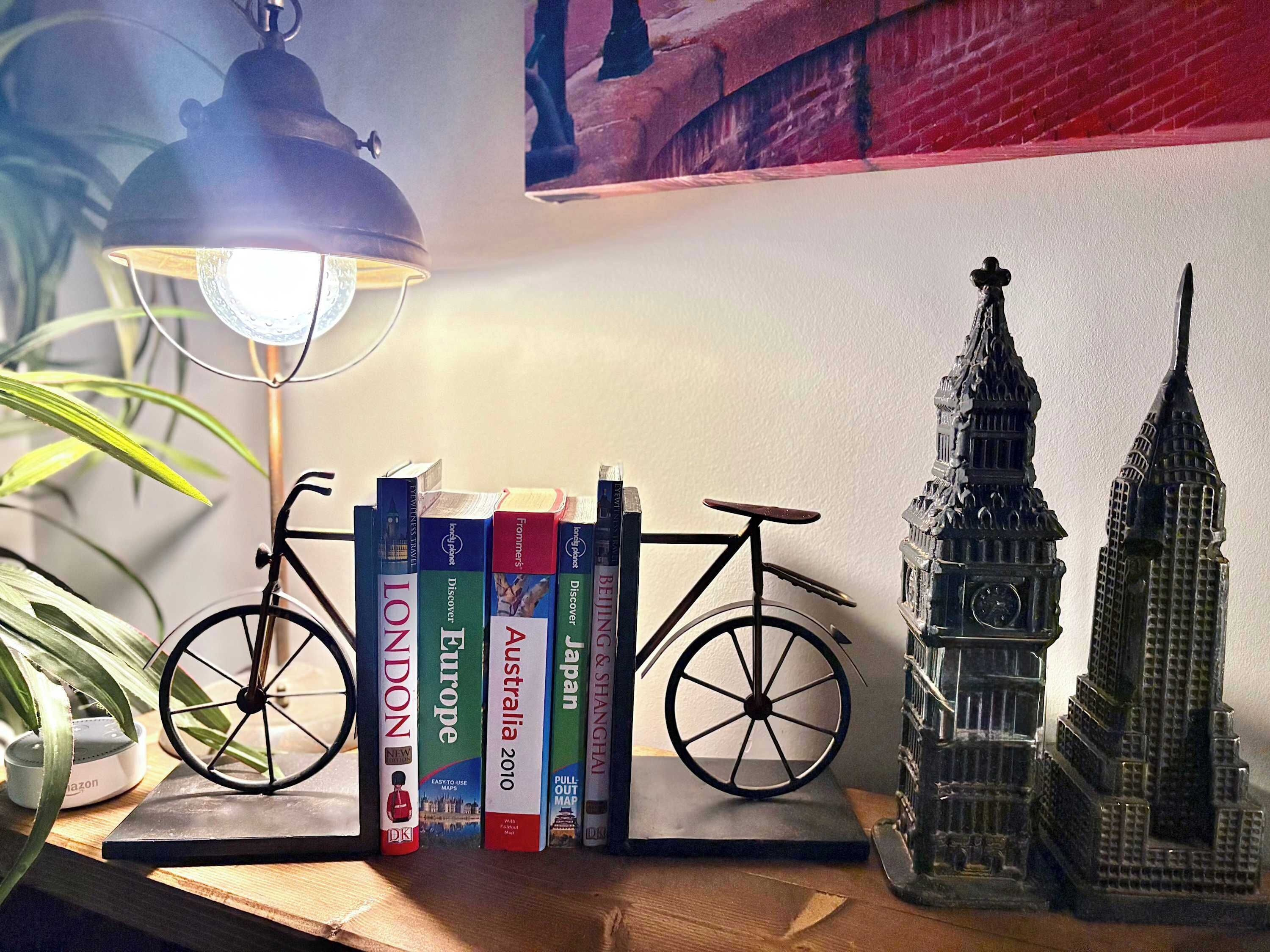 A bookshelf with travel books, a bicycle, and a model of the London Tower.