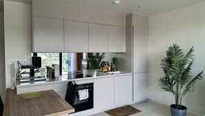 A modern kitchen with white cabinets, a black oven, and a dining area with a wooden table.