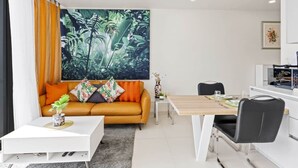 A modern living room with a sofa, coffee table, and a dining area with a table and chairs.