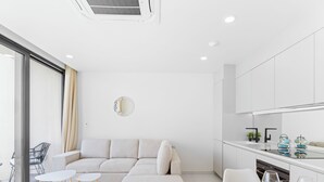 A modern living room with a sofa, a dining table with chairs, and a kitchen area with cabinets and a countertop. - C304 – 1 bedroom apartment with terrace (Sint Maarten)