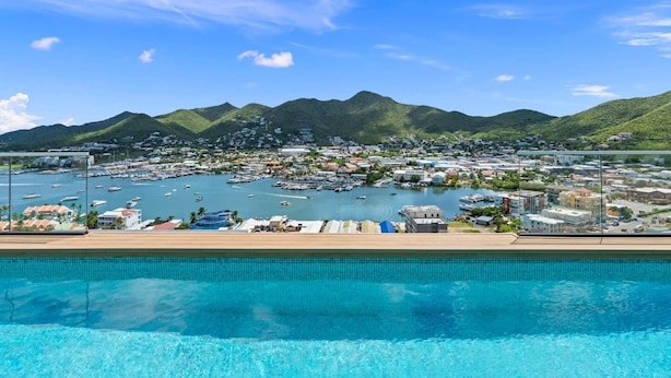 A coastal town with a marina, clear blue water, and mountains in the background. - C304 – 1 bedroom apartment with terrace (Sint Maarten)