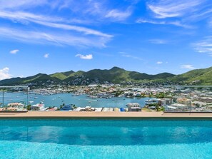 Eine Küstenstadt mit einem Yachthafen, klarem, blauem Wasser und Bergen im Hintergrund.