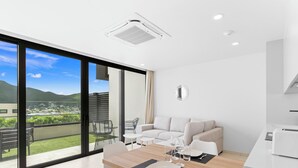 A modern dining area with a wooden table, white chairs, and a city view through large windows. - C304 – 1 bedroom apartment with terrace (Sint Maarten)