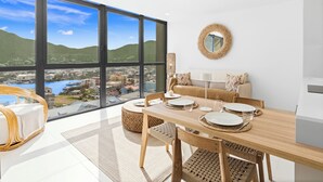 Ein moderner Essbereich mit großem Fenster und Blick auf eine malerische Stadtlandschaft und Hügel.