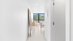 Ein moderner Flur mit Holzboden, weißen Wänden und einer Tür, die in einen Raum mit Bergblick führt.