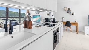 Cozinha moderna com uma ilha grande, área de jantar com vista e um espaço de trabalho com escrivaninha e cadeira.