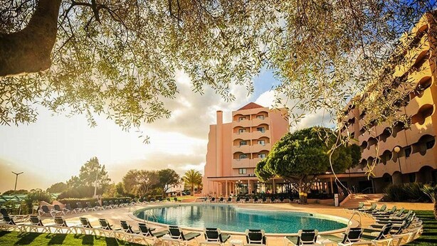 Ein Hotel mit Pool, Liegestühlen und einem Gebäude mit außergewöhnlichem architektonischem Design.